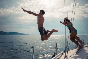 people jumping from a sailboat